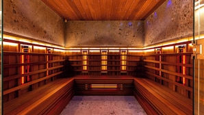 Un sauna avec des bancs et des murs en bois, équipé d’éléments chauffants rouges.