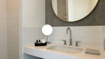 A modern bathroom with a white sink, a round mirror, and a towel on the counter.