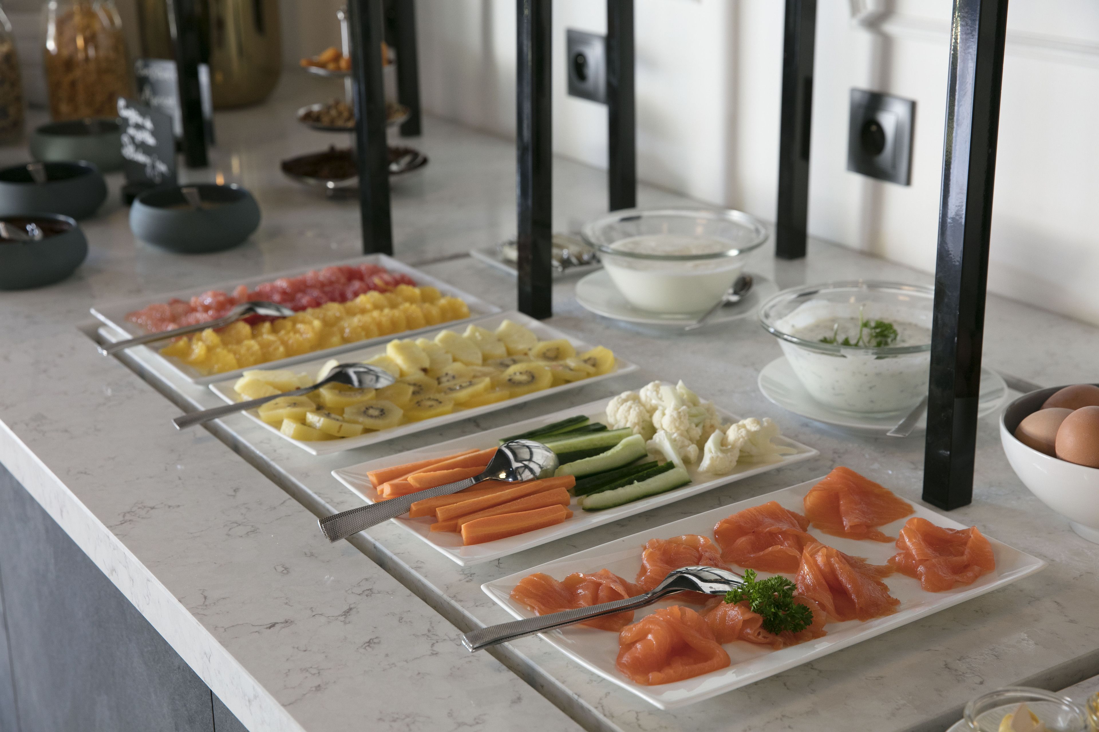 Un buffet proposant une variété de plats, notamment du saumon, des fruits et des légumes.