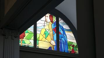 Una ventana de vitral con una persona sosteniendo una rama.