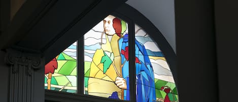 A stained glass window with a person holding a branch.
