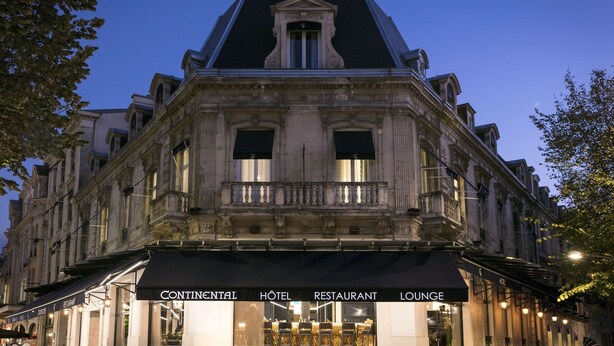 Un bâtiment historique surmonté d’un auvent noir où l’on peut lire : « HÔTEL CONTINENTAL, RESTAURANT, SALON ».