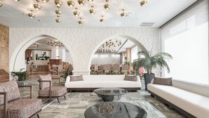 A spacious lobby with a marble floor, a central seating area, and a kitchen visible through an archway. - Civitel Akali Hotel (Chania)