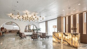 A spacious lobby with a marble floor, a reception desk, seating area, and a large arched doorway leading to another room. - Civitel Akali Hotel (Chania)