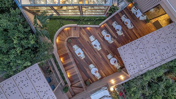 An aerial view of a rooftop restaurant with a wooden deck, white round tables, and chairs. - Civitel Akali Hotel (Chania)