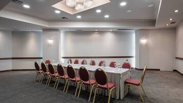 A conference room with a long table, red chairs, and a chandelier.