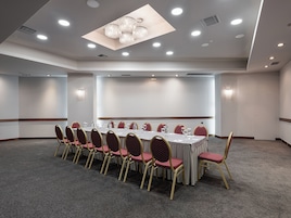 Un salón de conferencias con una larga mesa, sillas rojas y una araña de cristal.