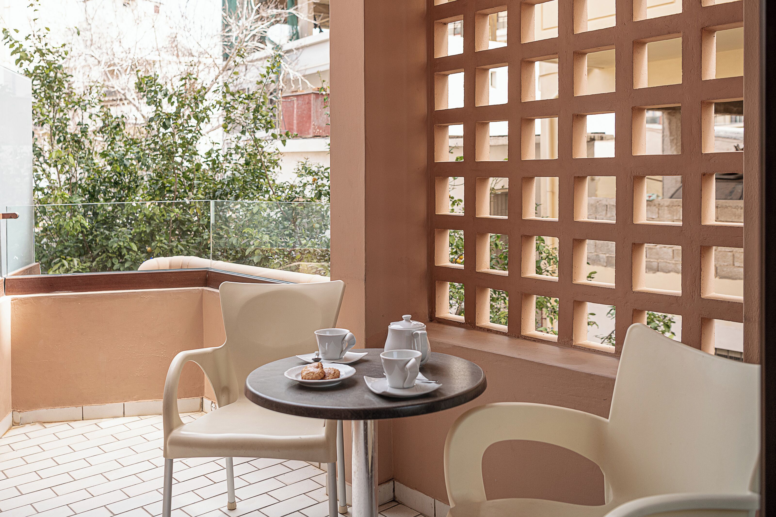 A balcony with a table set for two, chairs, and a decorative screen.