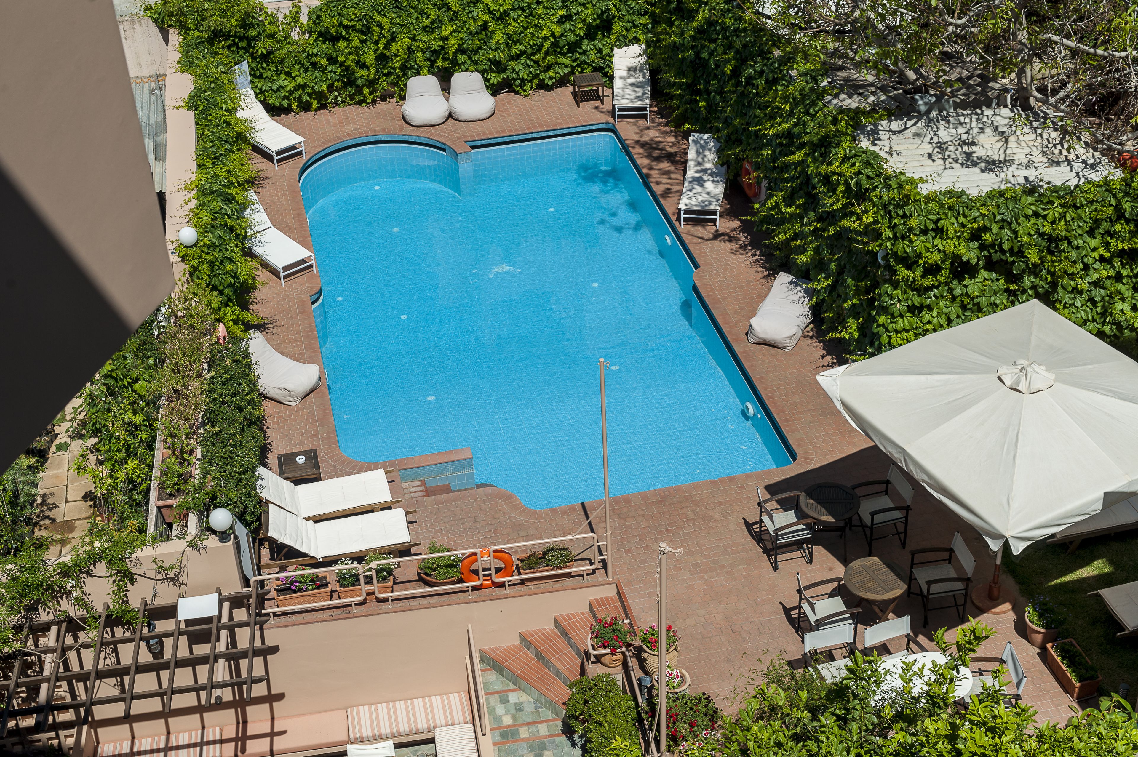 A rectangular swimming pool surrounded by lounge chairs and a covered seating area.
