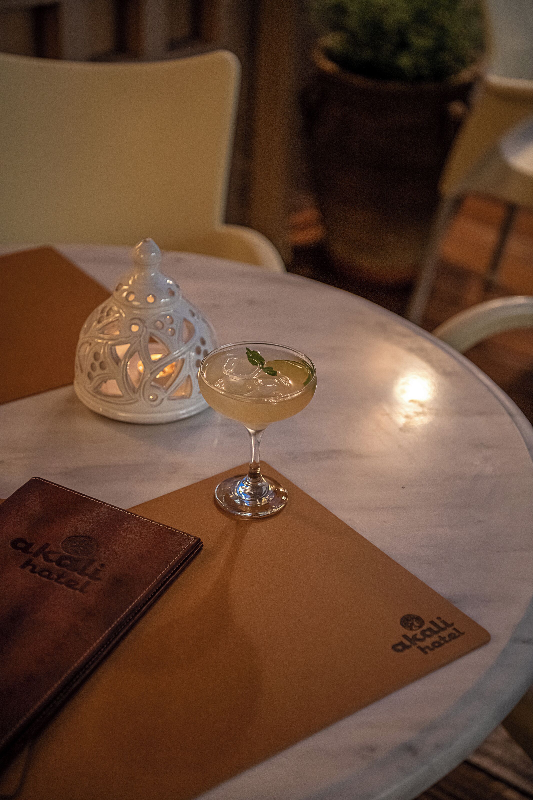 A table with a martini glass, a menu, and a decorative lantern.