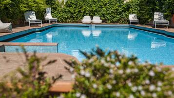 A swimming pool with white lounge chairs and a brick border.