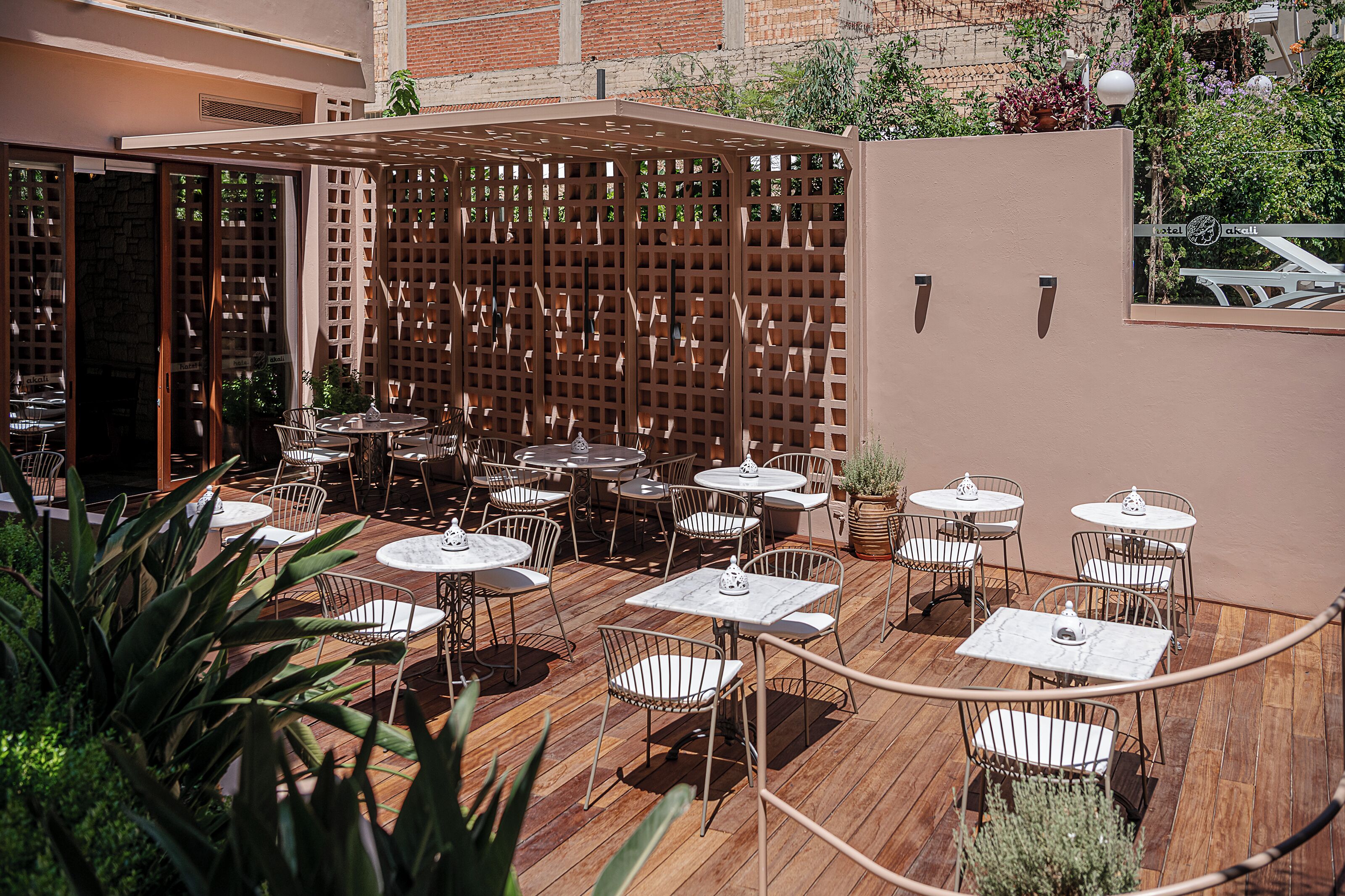 An outdoor patio area with multiple tables and chairs, a wooden deck, and a lattice partition.