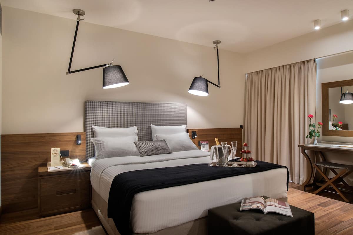 Ein modernes Hotelzimmer mit einem großen Bett, Nachttischen, einem Schreibtisch und einem Spiegel.