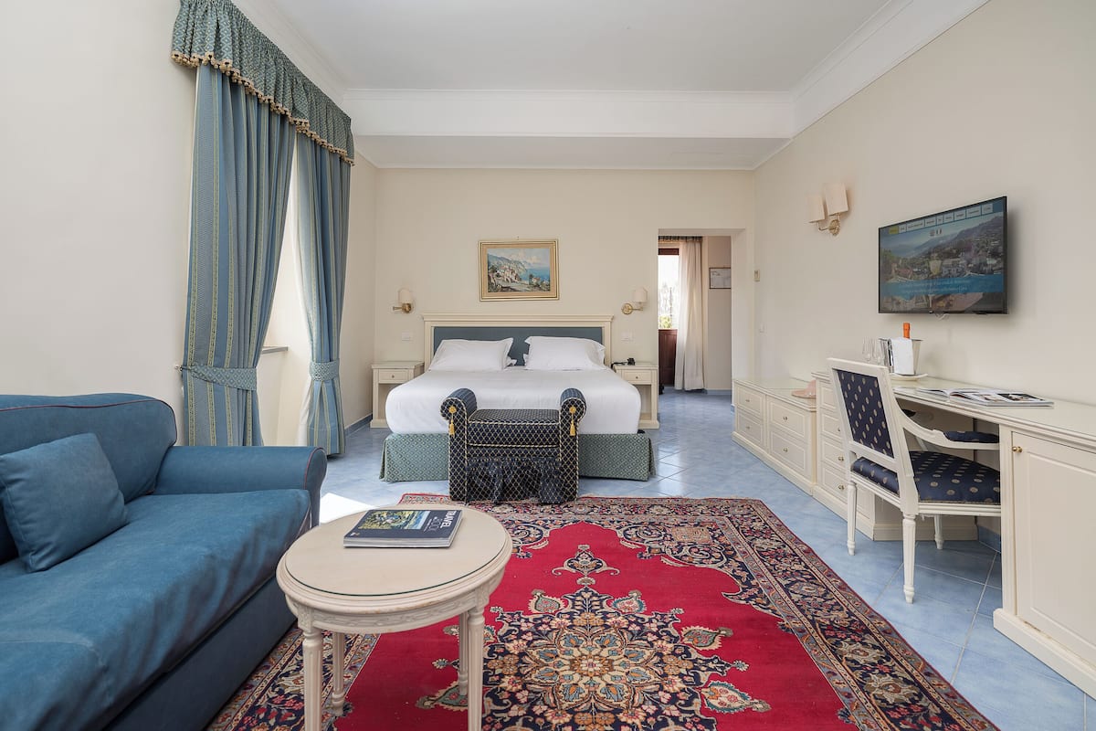 Une chambre d’hôtel avec un lit, un bureau, une chaise, un canapé et une moquette.