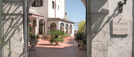An archway leading to a courtyard with potted plants and a sign reading "Ristorante Iaccarino".