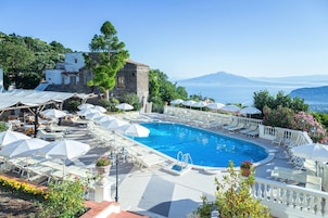 Una piscina al aire libre, sombrillas, sillones reclinables de piscina