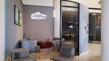 Um lobby moderno com áreas de estar, um bar e uma parede decorativa com uma nuvem de pensamento.