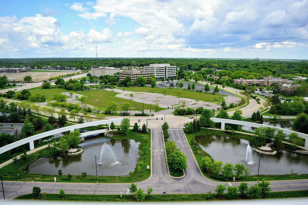 A large, open campus with multiple buildings, green spaces, and a central water feature with fountains.