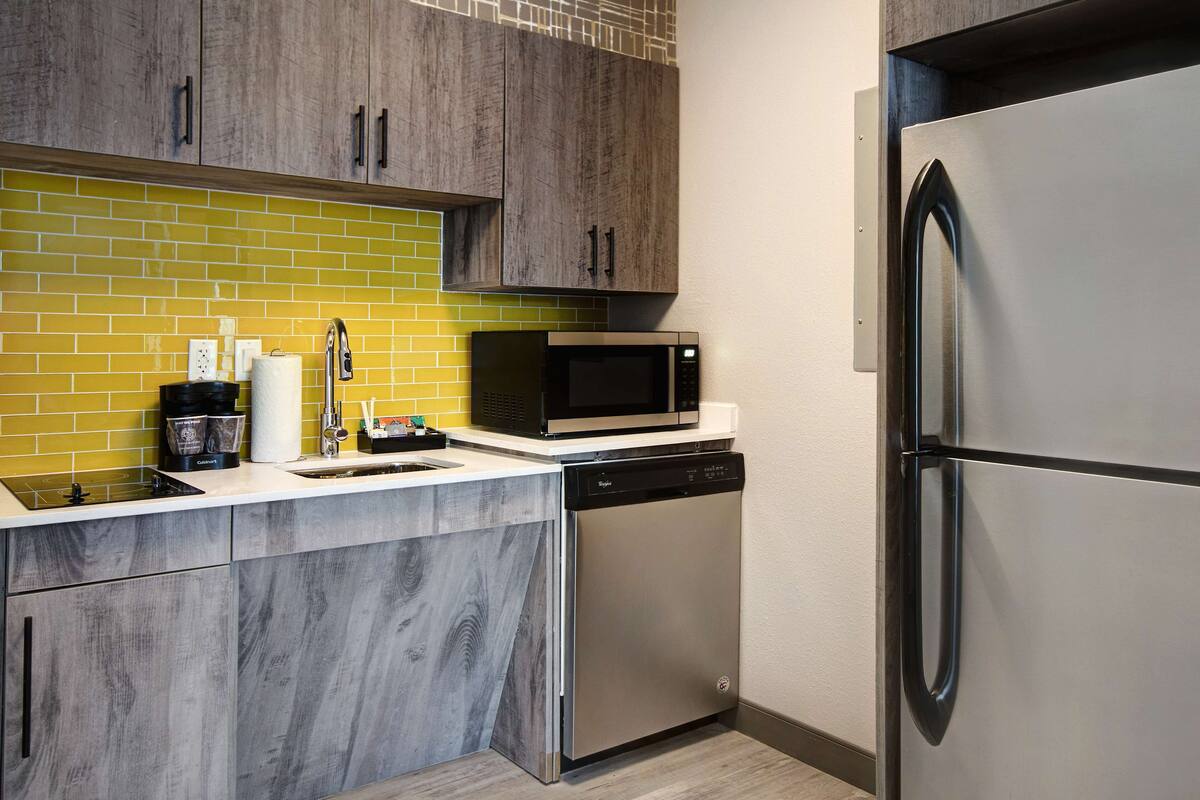 A modern kitchen with a stainless steel refrigerator, a built-in microwave, and a dishwasher.