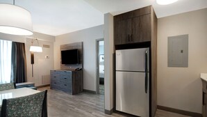 Une cuisine moderne dotée d’un réfrigérateur en acier inoxydable, de meubles en bois et d’un téléviseur à écran plat fixé au mur.