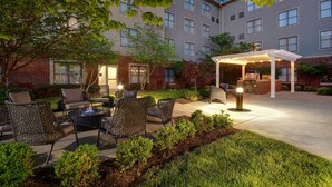 Un espace extérieur aménagé en terrasse, avec des meubles en osier, un foyer et un coin salon abrité.