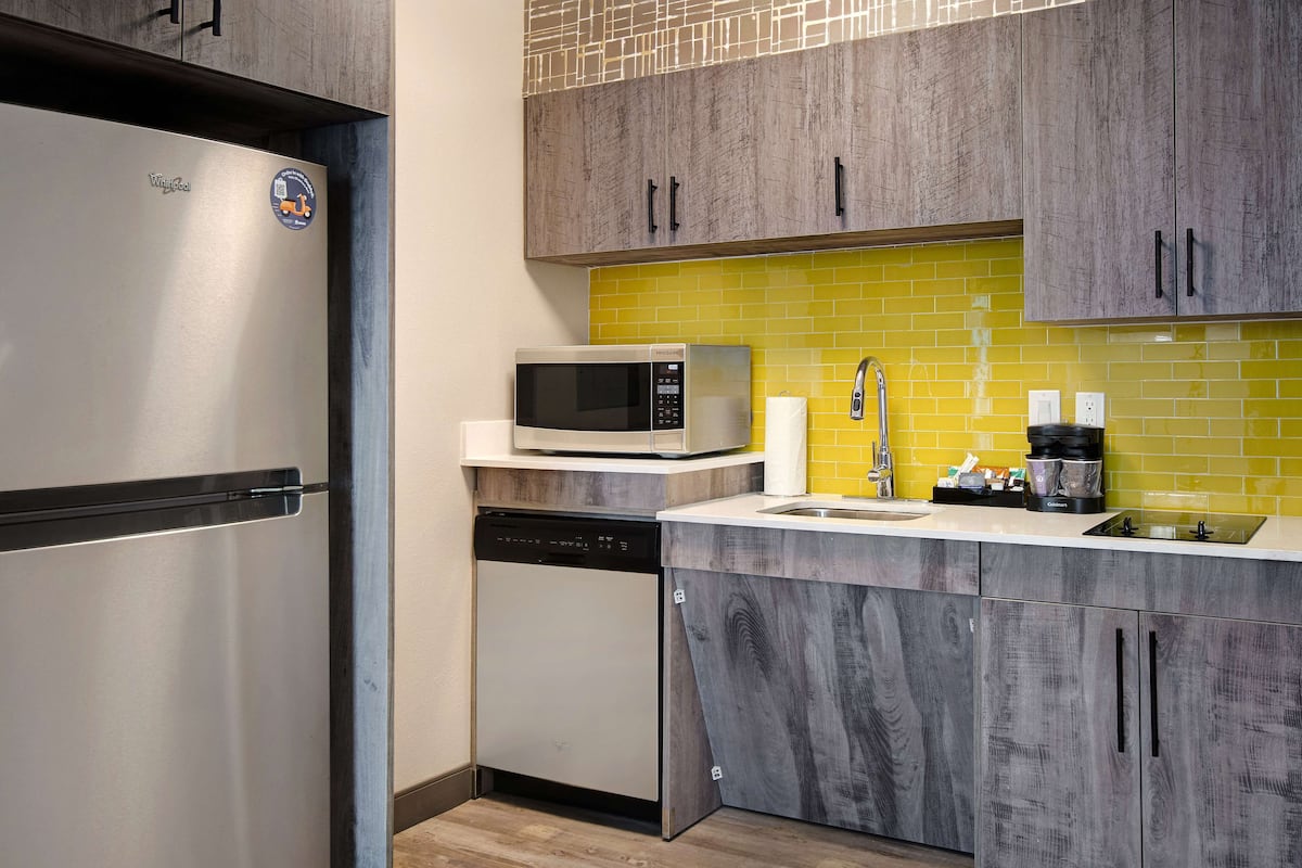 A compact kitchen with a stainless steel refrigerator, a microwave, and a dishwasher.