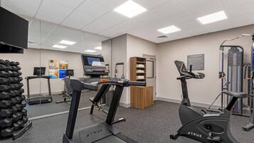 Un gimnasio con cintas de correr, elípticas y pesas sueltas.
