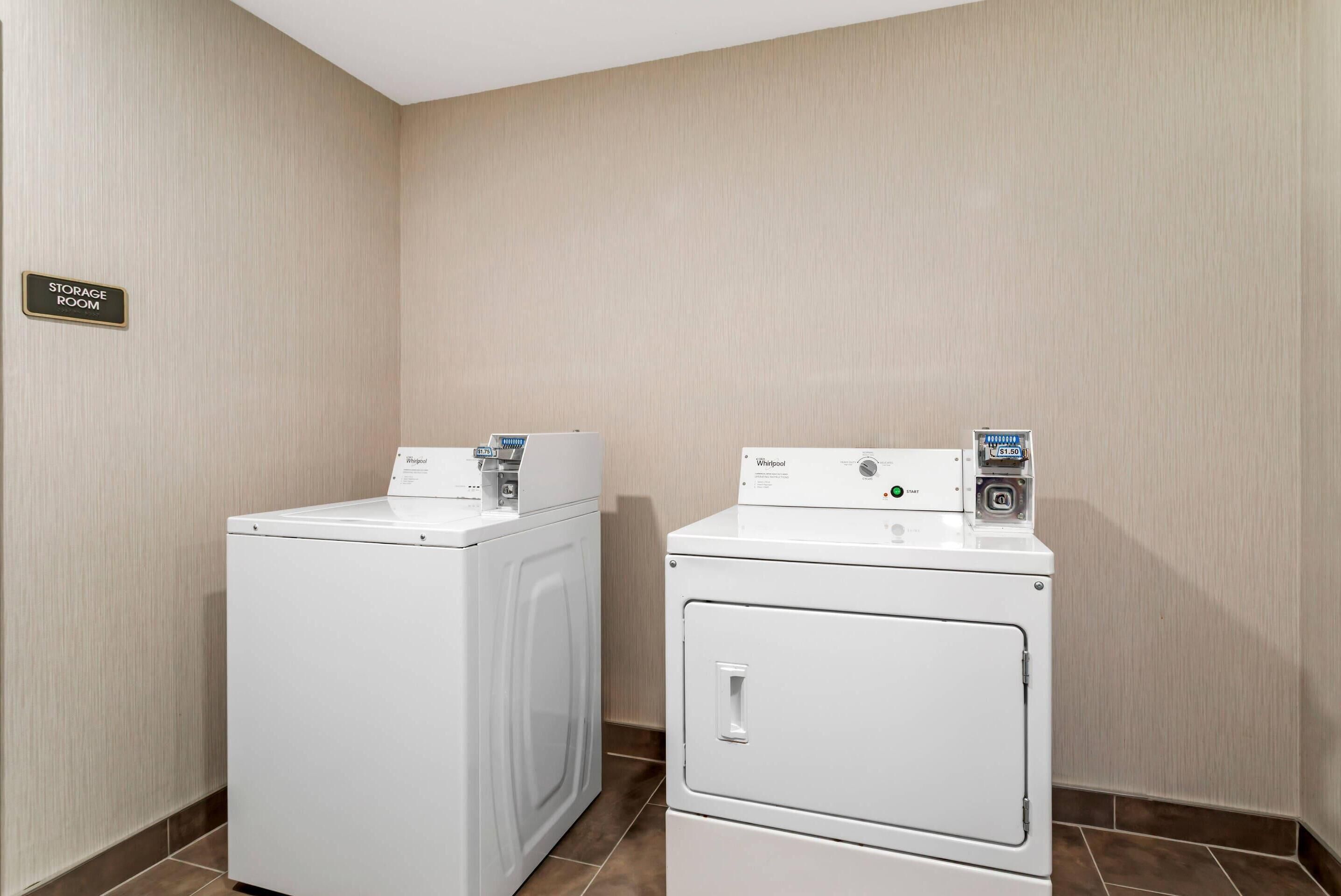 Un lavadero con dos lavadoras Whirlpool blancas y un cartel que indica depósito.