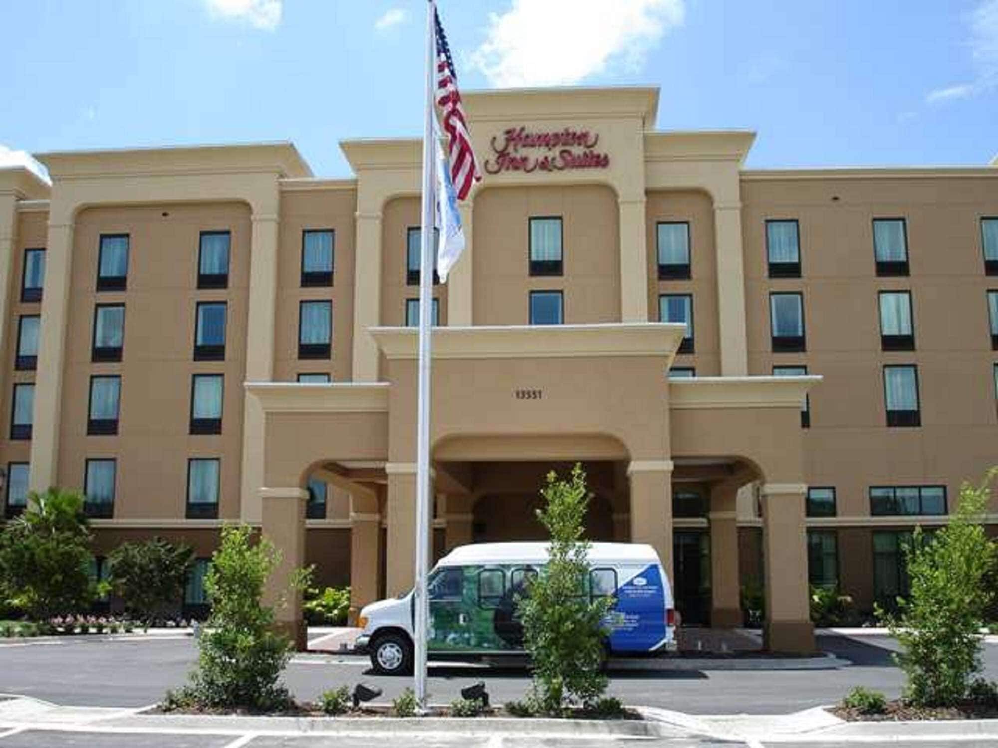 Un hotel con fachada color beige, múltiples ventanas y una bandera estadounidense.