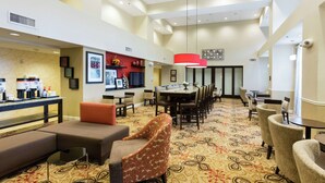 A hotel lobby with a reception area, seating arrangements, and a patterned carpet.