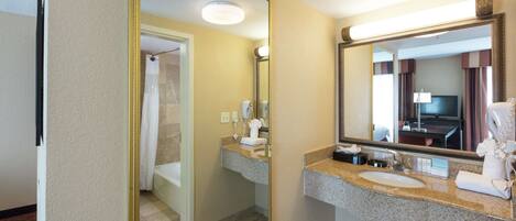 A hotel bathroom with a sink, mirror, and shower area.