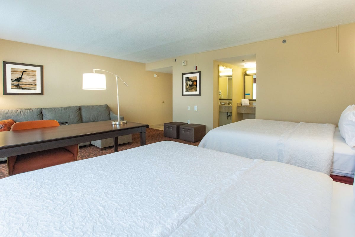 Une chambre d’hôtel avec deux lits, un canapé, un bureau et une lampe.