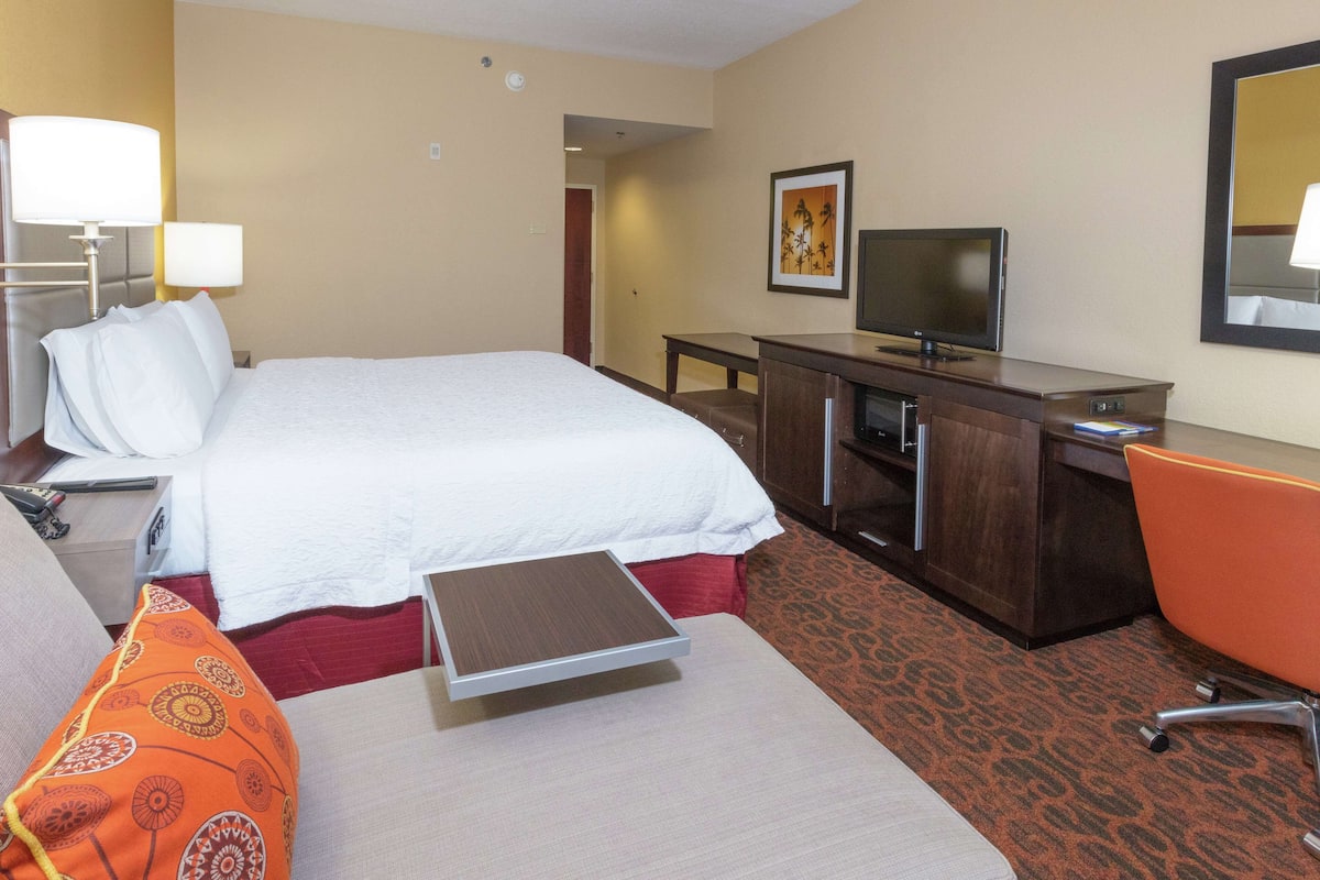 Une chambre d’hôtel avec un lit, un bureau, une télévision et une chaise.