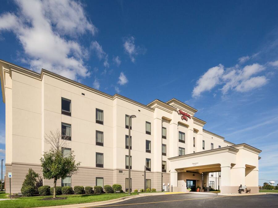 A large, beige hotel with a flat roof and symmetrical facade, featuring a central entrance with a covered walkway.