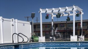 A swimming pool with a white pergola and hanging flower baskets. - Super 8 by Wyndham Ontario (Ontario)