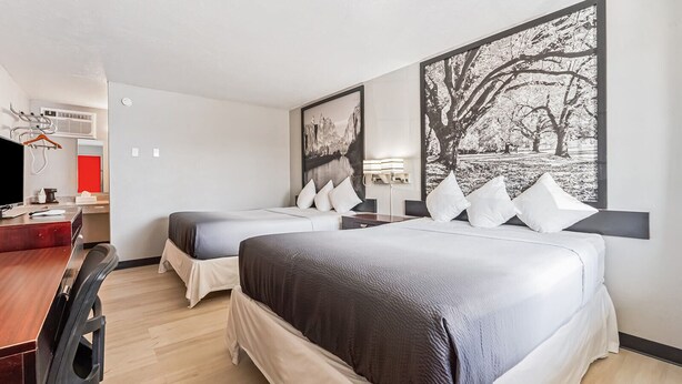 A hotel room with two beds, a desk, a chair, and artwork on the walls. - Super 8 by Wyndham Ontario (Ontario)