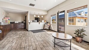 A reception area with a wooden floor, a reception desk, a coffee machine, and a Red Bull refrigerator. - Super 8 by Wyndham Ontario (Ontario)