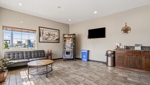 A hotel lobby with a sofa, coffee machine, trash bins, and a TV on the wall. - Super 8 by Wyndham Ontario (Ontario)
