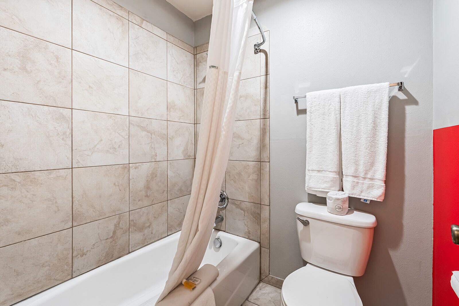 A bathroom with a bathtub, toilet, and shower curtain.