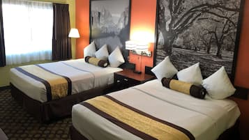 A hotel room with two beds, a nightstand with a lamp, and two framed pictures on the wall.