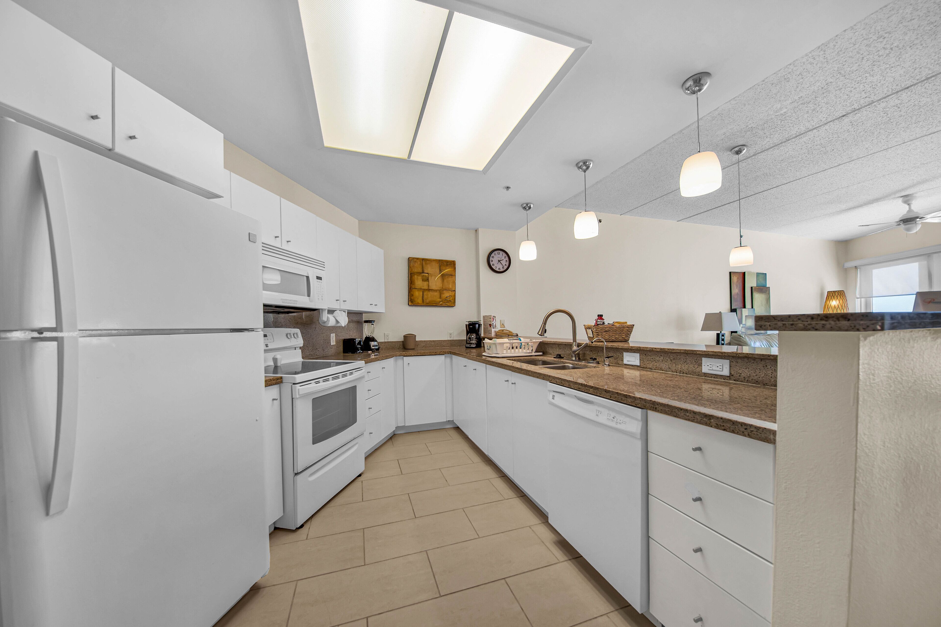 A modern kitchen with white cabinetry, a central island, a built-in oven, and a microwave.