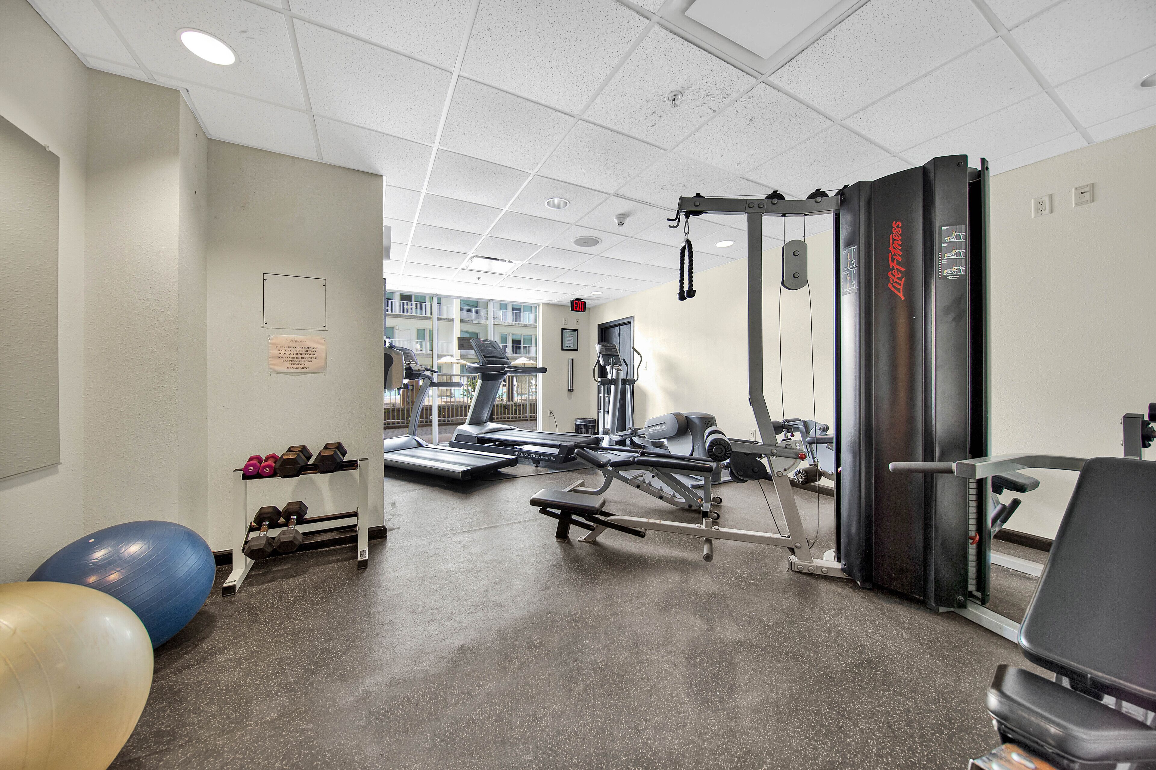 A gym with exercise equipment, a treadmill, and exercise balls.