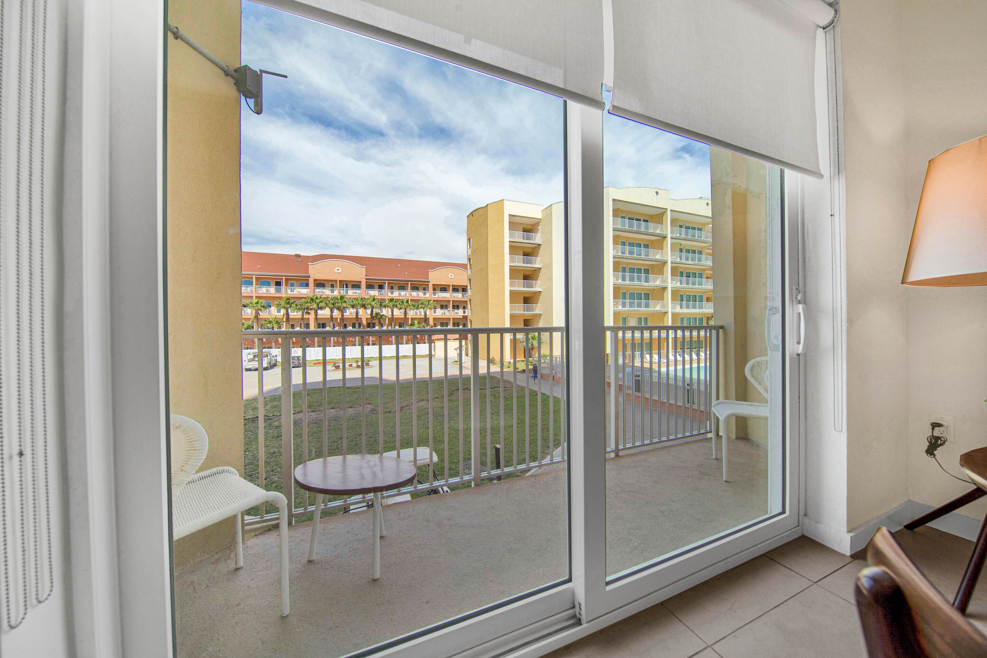 Varanda com vista para um conjunto de edifícios, uma mesa e duas cadeiras.