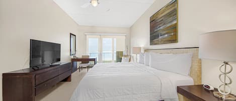 A hotel room with a large bed, a TV, a desk, and a balcony view.