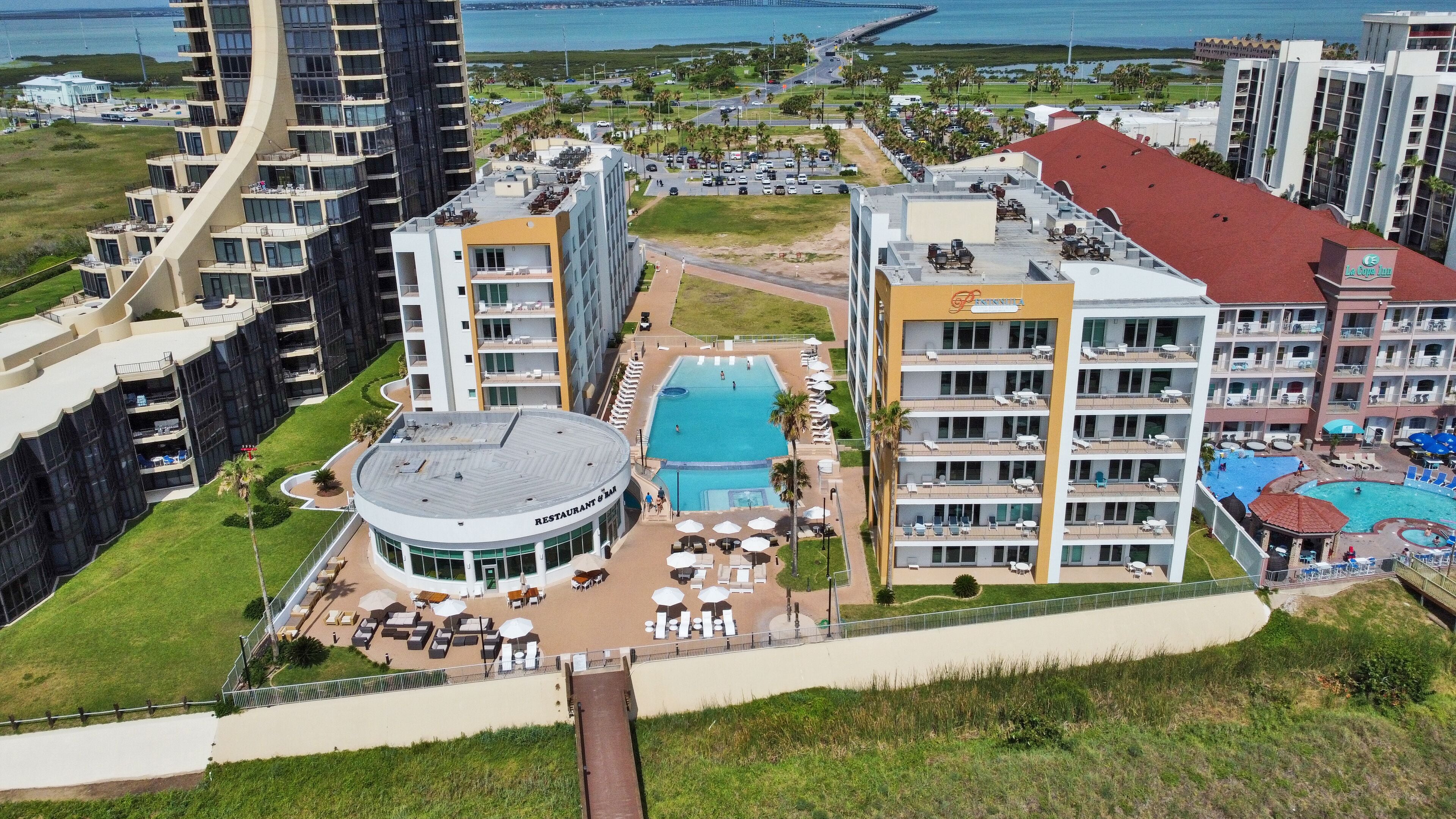 Hotel alto com piscina no terraço, várias varandas e um restaurante.