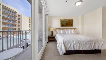 Una habitación de hotel con balcón, una cama, una mesita de noche y un cuadro en la pared.