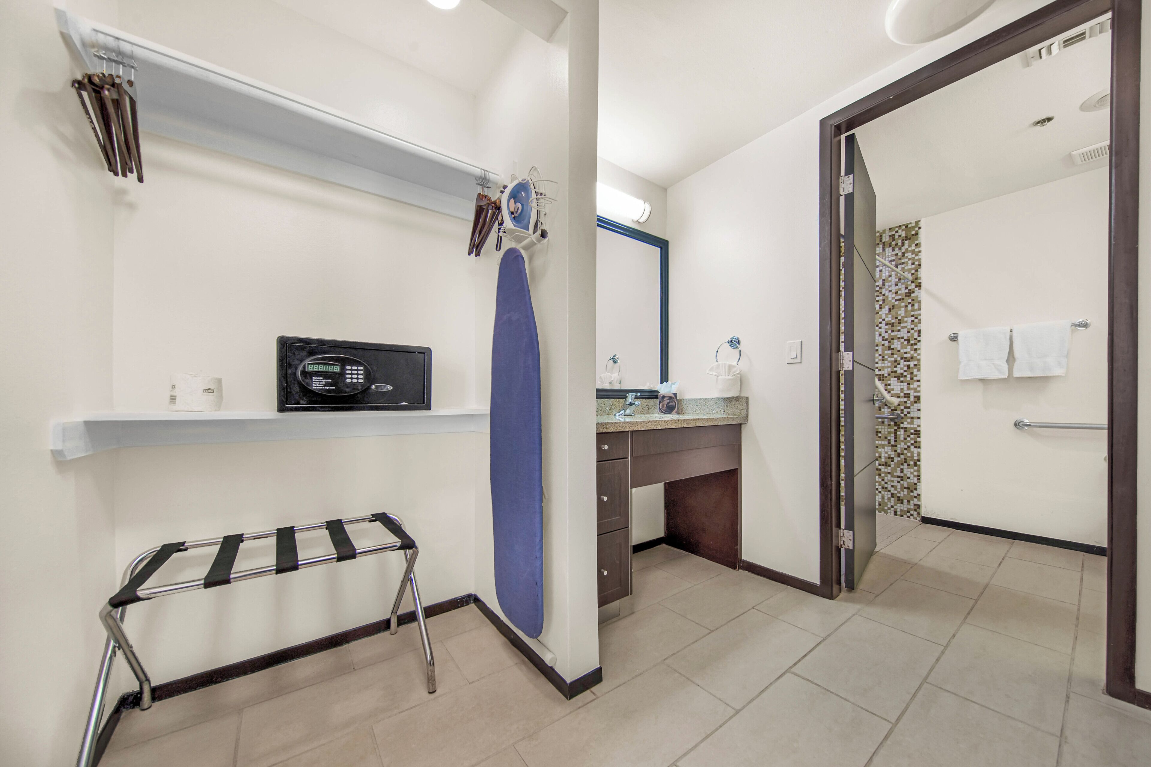 A modern bathroom with a shower, a sink, and a mirror. There is a towel rack and a drying rack.