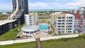A hotel with a pool, multiple floors, and a view of the ocean.