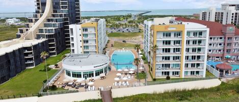 A hotel with a pool, multiple floors, and a view of the ocean.
