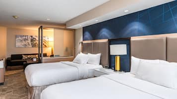 Ein Hotelzimmer mit zwei Betten, einem Sofa, einem Schreibtisch und einer Lampe.